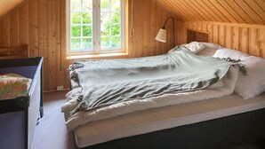 Una habitación de madera con una cama, una ventana y una lámpara.
