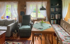 A cozy living room with a sofa, a chair, a dining table with a bench, a bookshelf, and a window with curtains. - Stunning home in Sandefjord with WiFi (Sandefjord)