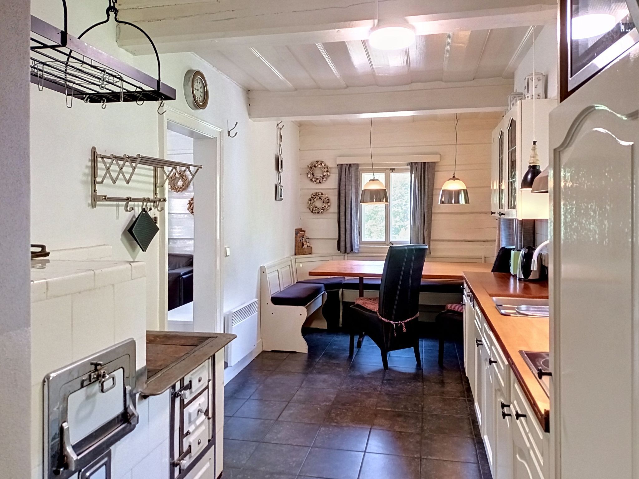 A compact kitchen with a dining area, a built-in oven, and a window with curtains.