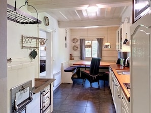 A compact kitchen with a dining area, a built-in oven, and a window with curtains. - Jizera cottage by Interhome (Rokytnice nad Jizerou)