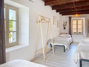 A room with three beds, a wooden drying rack, and a hanging plant. - Apartment Beo by Interhome (Colico)