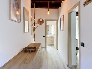 A hallway with a wooden counter, a mirror, and a hanging light fixture. - Apartment Beo by Interhome (Colico)