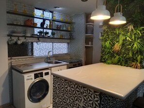 Eine Küche mit Waschmaschine, Spüle und Regalen voller Küchenutensilien.