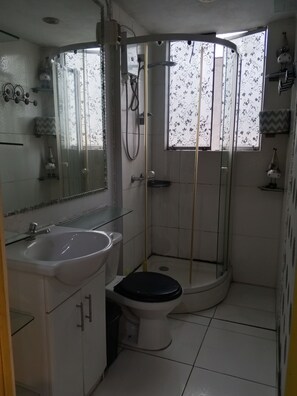 Ein Badezimmer mit Toilette, Waschbecken, Dusche und Spiegel.