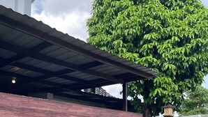 A building with a modern design, featuring a wooden panel wall, a covered entrance, and a large tree in the background. - Saren Muding, a private, charming 2BR corner house in Kerobokan. (Tabanan, Tabanan Regency)