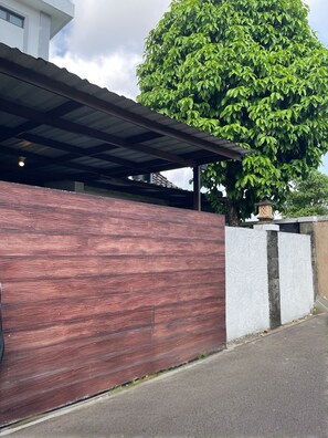 Ein Gebäude mit modernem Design, mit einer Holzwand, einem überdachten Eingang und einem großen Baum im Hintergrund.