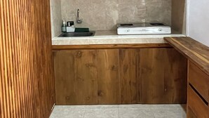 A compact kitchen with wooden cabinets, a countertop, a sink, and a stove. - Saren Muding, a private, charming 2BR corner house in Kerobokan. (Tabanan, Tabanan Regency)