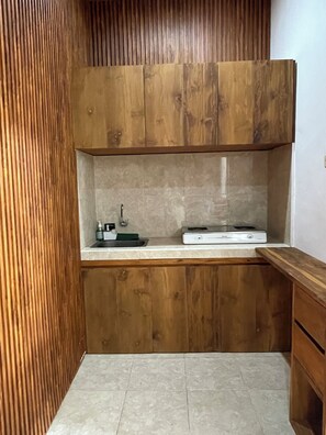 Eine kleine Küche mit Holzschränken, einer Arbeitsplatte, einem Spülbecken und einem Herd.