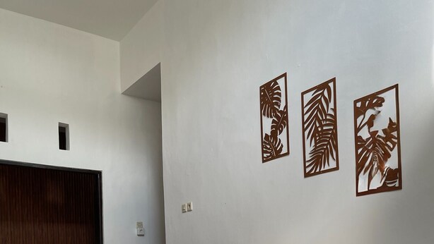 A room with a sofa, two wicker chairs, a small round table, and decorative wall art. - Saren Muding, a private, charming 2BR corner house in Kerobokan. (Tabanan, Tabanan Regency)