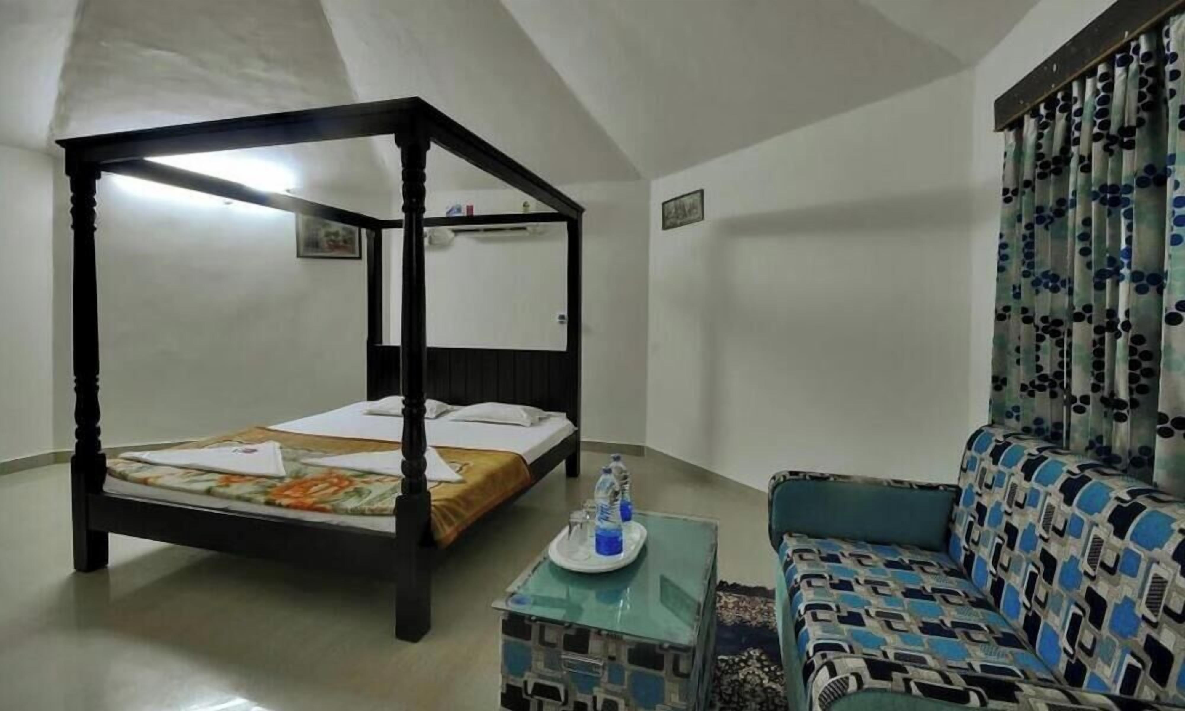 Habitació amb llit baldaquí, un sofà, una taula petita amb una bandeja i una cortina amb dibuixos.