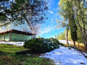 A residential property with a two-story house, a covered porch, and a snow-covered yard.