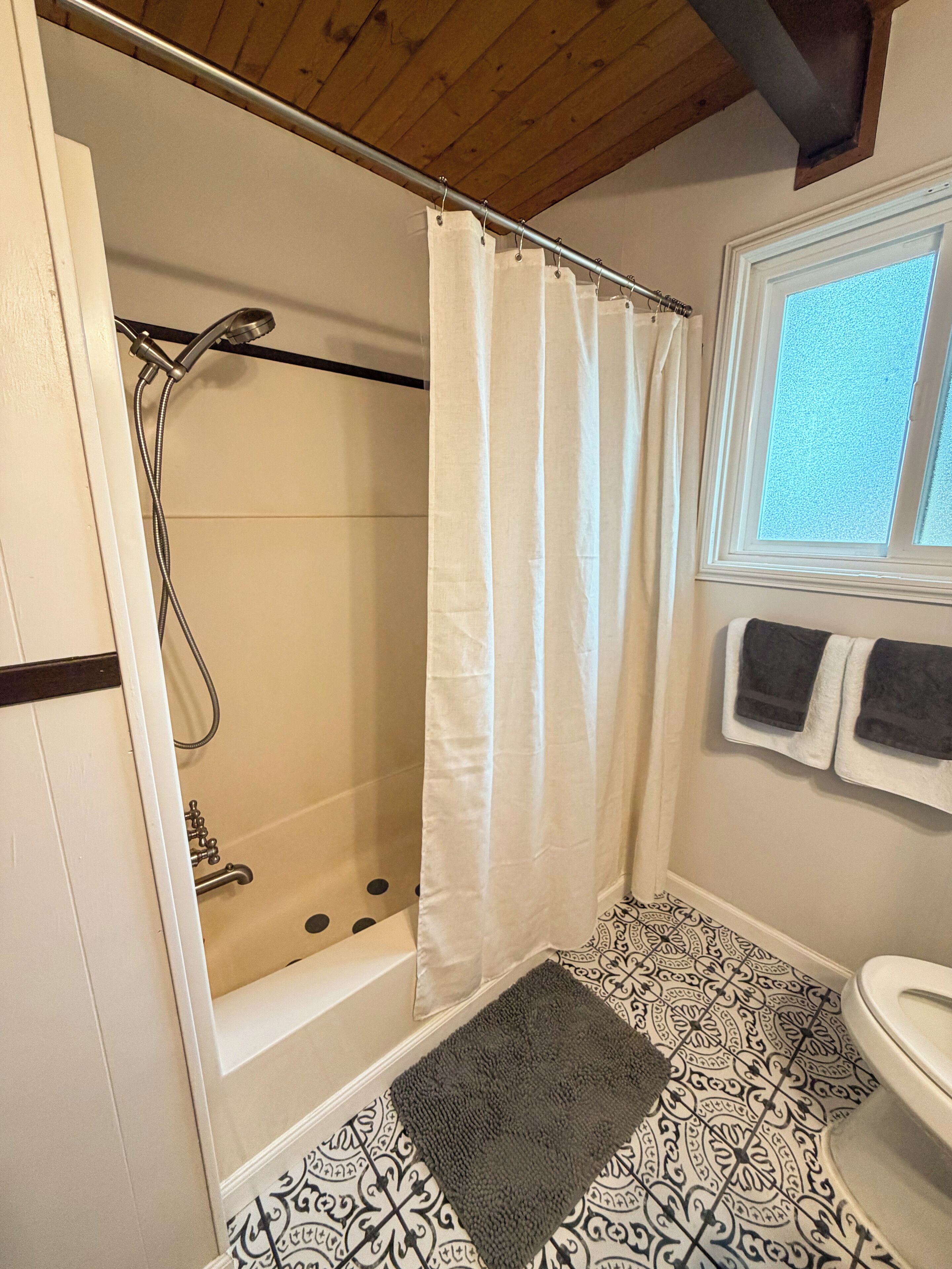 A bathroom with a shower, a bathtub, a sink, and a window.