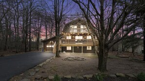 A two-story log cabin with a front deck, garage, and a stone pathway leading to the entrance. - Mtn Retreat |Hot tub |Firepit |Theatre& Game Rooms (Tobyhanna)