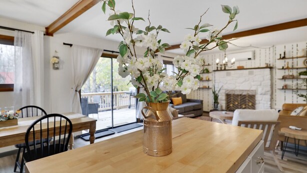 A wooden dining table with a vase of white flowers in the center, surrounded by chairs. - Mtn Retreat |Hot tub |Firepit |Theatre& Game Rooms (Tobyhanna)