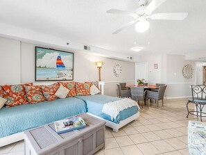 Ein Wohnzimmer mit einer Couch, einem Couchtisch, einem Essbereich mit Stühlen und einem Deckenventilator.