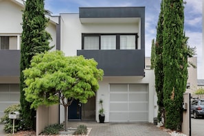 Ein modernes, zweistöckiges Haus mit Garage, Briefkasten und Blumentopf.