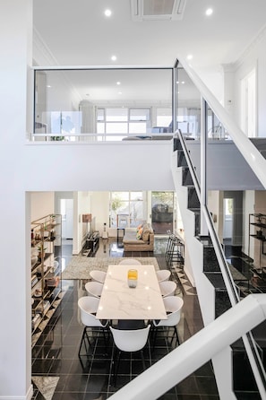 A modern interior with a dining area, staircase, and open-plan living space. - Ocean View Adelaide Escape - North Haven (North Haven)