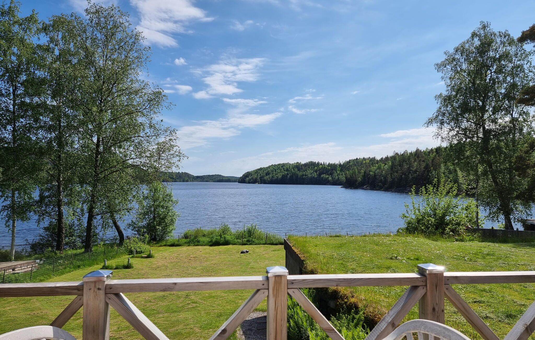 Utsikt över sjön med en träaltan och en gräsyta.