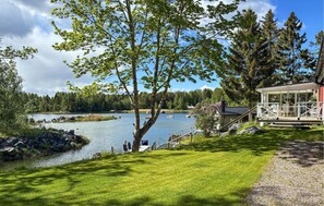 A lakeside property with a wooden deck, a small cabin, and a grassy area. - Cozy home in Axmar with sauna (Axmar)