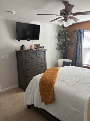 A bedroom with a bed, a dresser, a television, a ceiling fan, a plant, and a window with curtains. - 3BR Townhouse 3 min to I-20, Exit 11 (Graniteville)