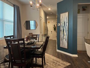 A dining area with a table, chairs, a chandelier, and a large abstract painting on the wall. - 3BR Townhouse 3 min to I-20, Exit 11 (Graniteville)