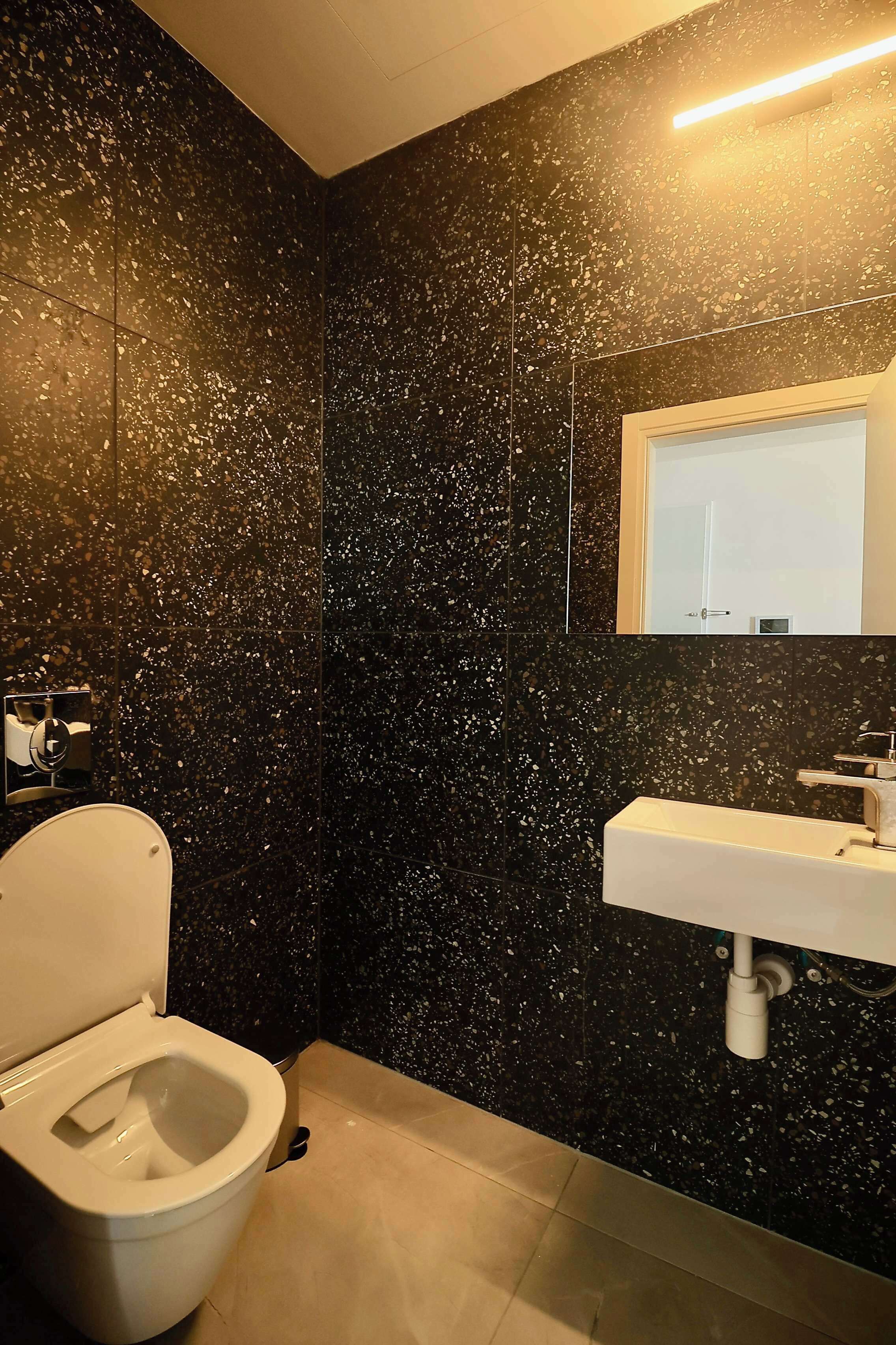 A bathroom with a toilet, sink, and mirror.