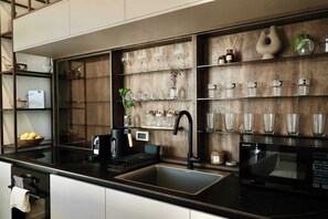 Eine moderne Küche mit schwarzem Arbeitsplatz, einer integrierten Spüle, einer Kaffeemaschine und einer Mikrowelle.