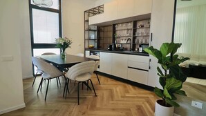 Une cuisine moderne avec un coin repas, un plancher en bois et une plante en pot.