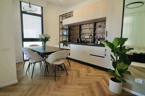 Eine moderne Küche mit Essbereich, Holzboden und einem Blumentopf.