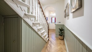 A hallway with a wooden staircase, a door, and a plant. - Sandy Boobies - Garden, Hot tub, Dog friendly (St Ives)