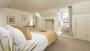 A bedroom with a bed, a bedside table, a mirror, a wardrobe, and a skylight. - Sandy Boobies - Garden, Hot tub, Dog friendly (St Ives)