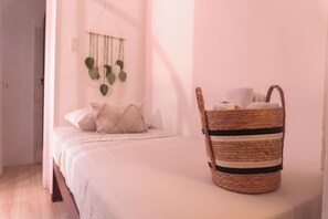Un dormitorio con una cama, una cesta tejida y una planta en la pared.