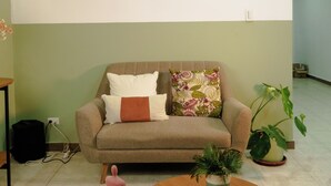 Ein Wohnzimmer mit einer Couch, einem Couchtisch, einer Pflanze und Kunstwerken an der Wand.