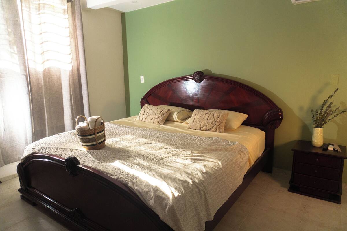 Un dormitorio con una cama de madera, una mesita de noche y un ventanal con cortinas.