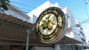 Ein rundes Schild mit dem Text 'Casa Guayabal Hostal Cocina Cafe Cartagena Colombia' und einer Illustration von Früchten.