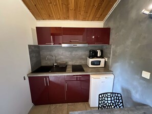Una cucina compatta con lavandino, forno a microonde e macchina del caffè sul piano di lavoro.