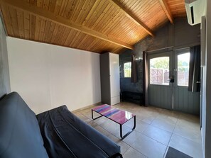 Una habitación con techo de madera, una banca, una mesa y una puerta que da al exterior.