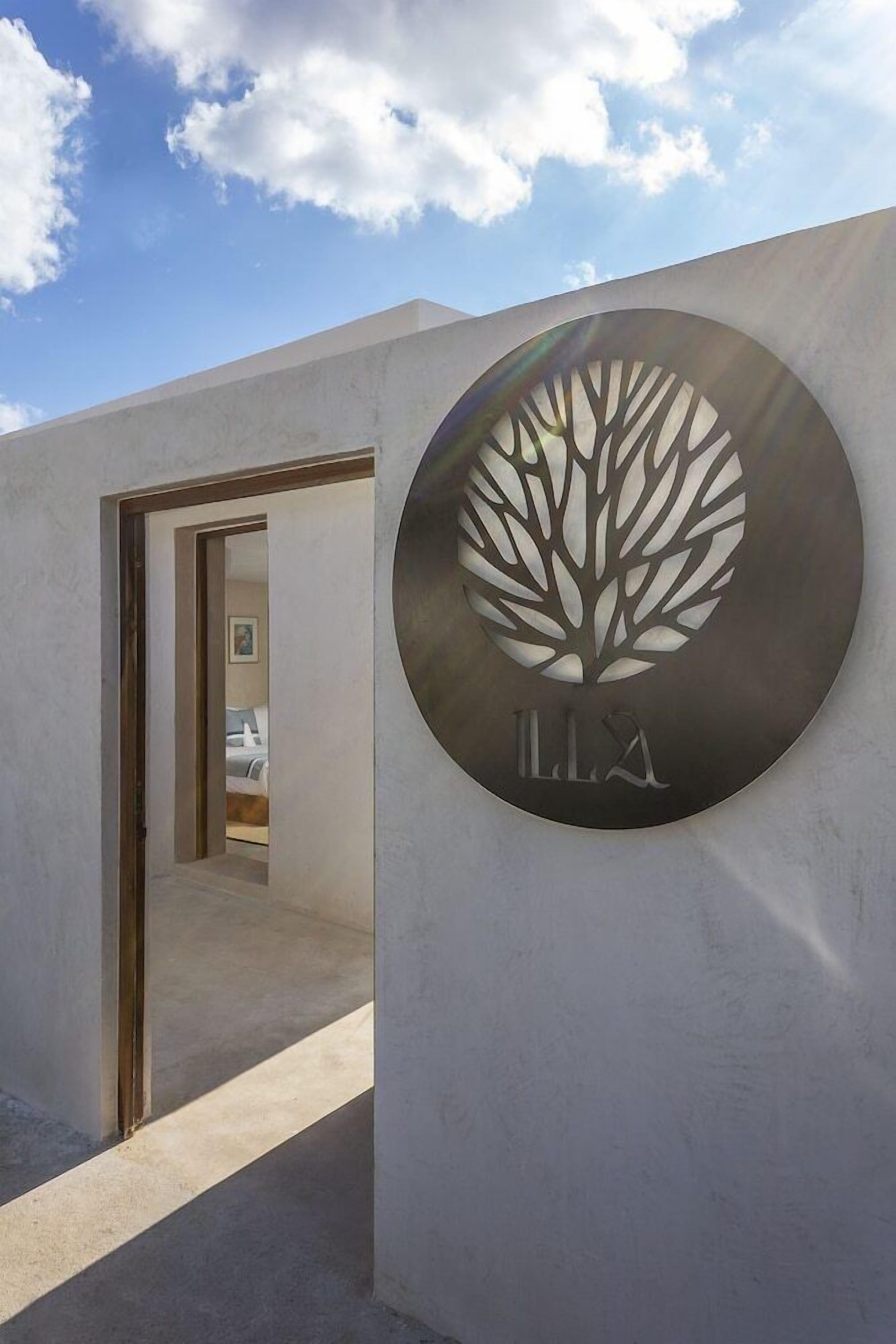 Una entrada moderna a un edificio con un letrero circular que presenta un diseño de árbol y las letras 'LLX' debajo.
