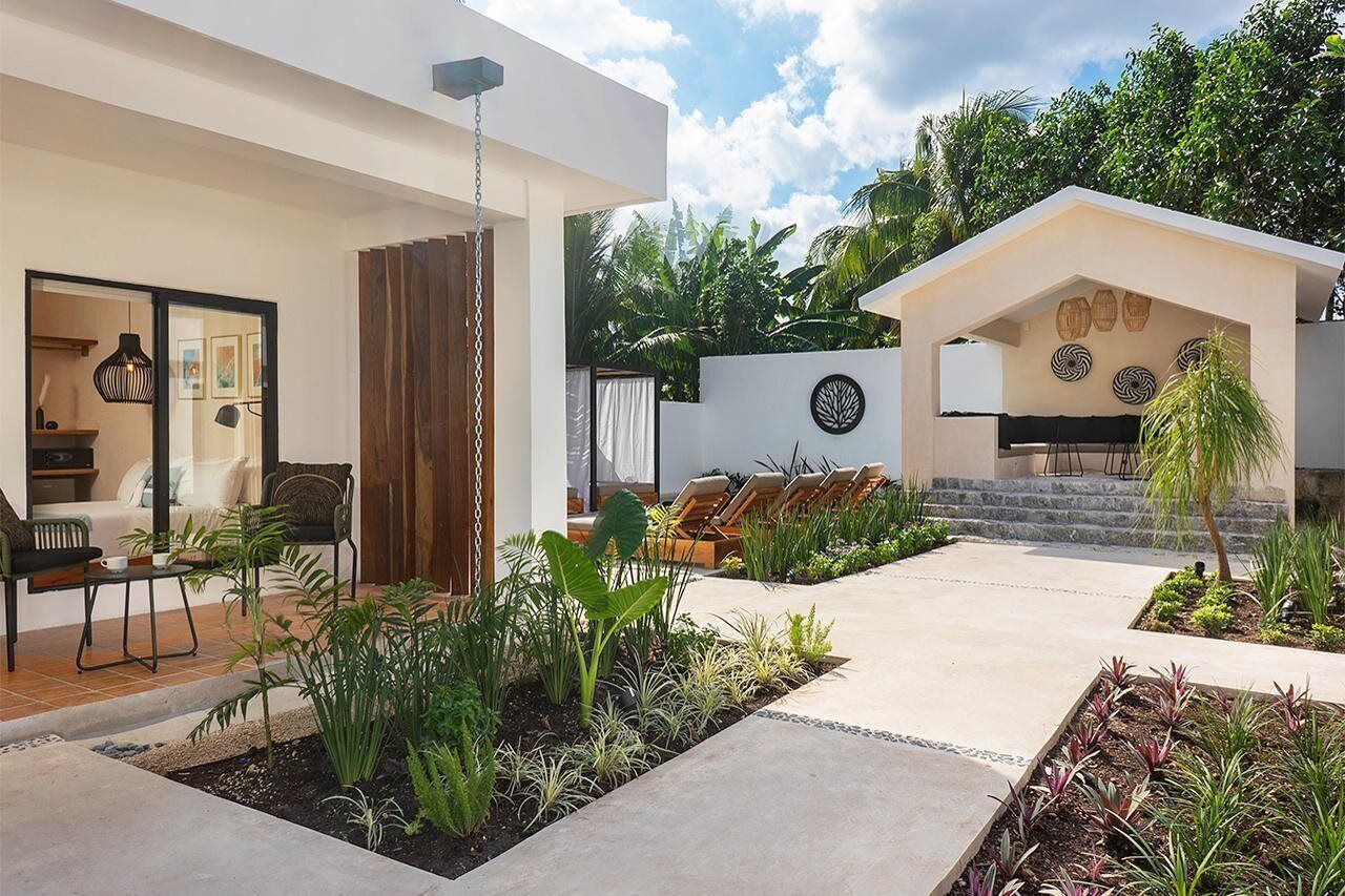 A modern outdoor patio with seating, a wooden privacy screen, and tropical plants.