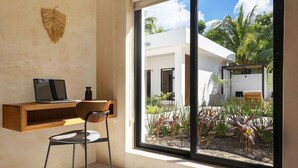 A modern room with a large window, a desk, a chair, and a decorative wall piece. - Illa Boutique Hotel Cozumel (Cozumel)