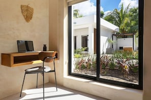 A modern room with a large window, a desk, a chair, and a decorative wall piece. - Illa Boutique Hotel Cozumel (Cozumel)