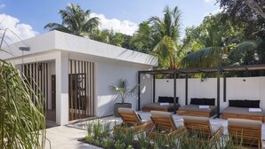A modern outdoor lounge area with seating, a pergola, and tropical vegetation. - Illa Boutique Hotel Cozumel (Cozumel)