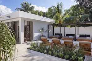 A modern outdoor lounge area with seating, a pergola, and tropical vegetation. - Illa Boutique Hotel Cozumel (Cozumel)