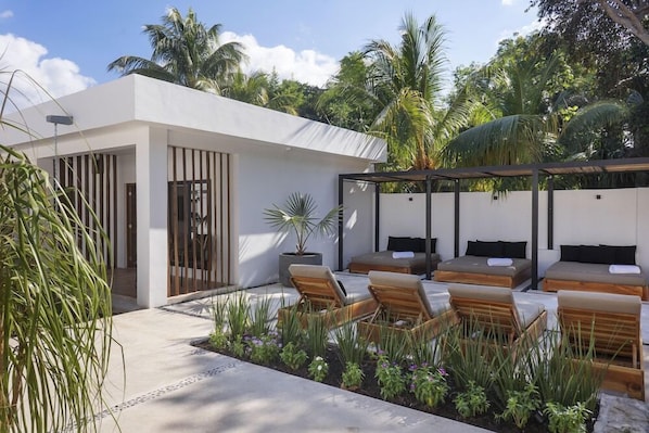 A modern outdoor lounge area with seating, a pergola, and tropical vegetation. - Illa Boutique Hotel Cozumel (Cozumel)