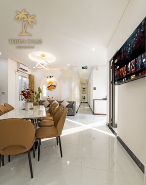 A modern hotel lobby with a dining area, a reception desk, and a large screen displaying movie options. - Terra Calm Mountain View Villa Da Nang (Da Nang)