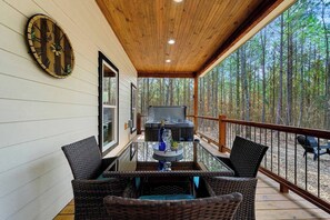 Eine überdachte Terrasse mit Korbmöbeln, einem Whirlpool und einer Holzbeschichtung.