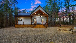 A cabin with a wooden deck, a front porch, and a gravel driveway. - Couples Retreat w/ Hot Tub, Jacuzzi, Fireplaces (Broken Bow)