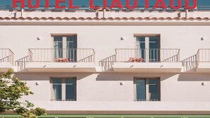 Een hotel genaamd 'HOTEL LIAUTAUD' met een witte gevel, meerdere balkons en ramen.