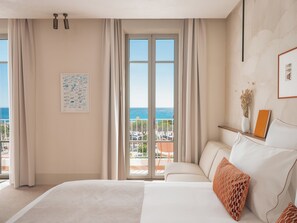 Habitación de hotel con una cama grande, vista al mar y un balcón.