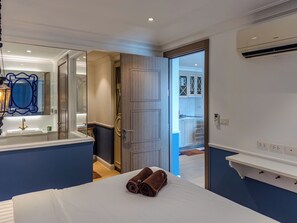 Ein Hotelzimmer mit Bett, Badezimmer mit Spiegel und Waschbecken, Kleiderschrank und Klimaanlage.
